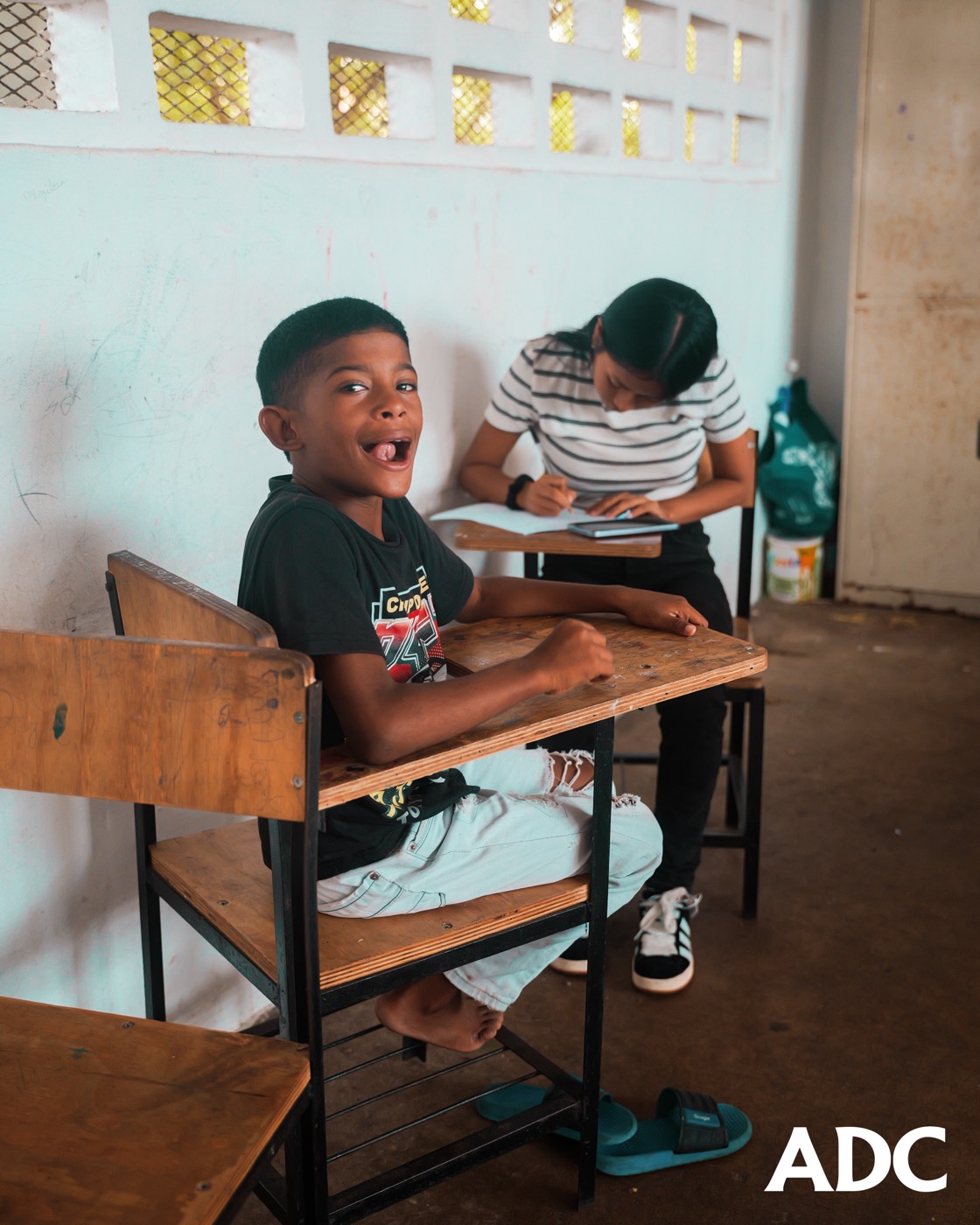 Estudiante de ADC sonriendo en una sesión de tutoría académica con una voluntaria